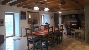 Un comedor con vigas de madera, chimenea y piso de baldosas.