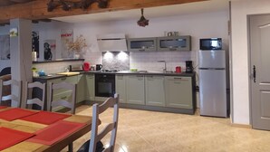 Una cocina con techo de madera, una mesa de comedor con individuales rojos y un refrigerador.