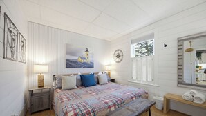 A bedroom with a bed, bedside tables, a bench, a window, a wall clock, and a painting. - Charming Retreat (Gloucester)