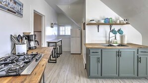 Una cocina con una mesa de madera, cocina a gas y armarios grises.