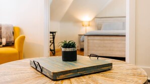 Una mesa redonda de madera con una bandeja metálica y una planta en maceta. Se ve parcialmente una silla amarilla a la izquierda.