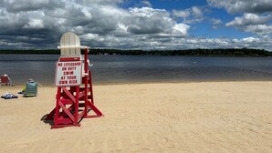 Una spiaggia con una postazione di salvataggio e un cartello che avvisa dell'assenza di bagnini.
