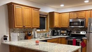 Una cucina moderna con mobili in legno, piani di lavoro in granito ed elettrodomestici in acciaio inossidabile.