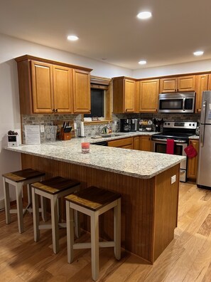 A modern kitchen with wooden cabinets, granite countertops, and stainless steel appliances.
