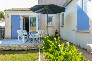 A patio with outdoor seating, a stone wall, and a large umbrella.