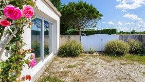 Una casa con jardín, un árbol y una cerca blanca.