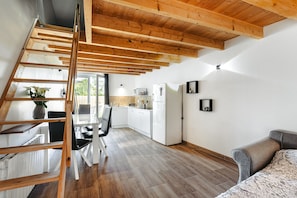 Une cuisine moderne avec des meubles blancs, un plafond en bois et un coin repas comprenant une table et des chaises.