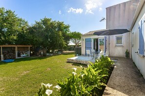 A backyard with a patio, a covered seating area, and a small shed.