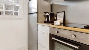 A compact kitchen with a refrigerator, coffee machine, and a framed certificate on the counter. - Prestigegoldresidence 1 – Historic Center Apartment with Wi-Fi and Air Conditioning (Guimarães)