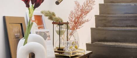 A staircase with a decorative vase, a framed book, and a small table with a glass container.