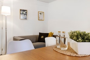 Une pièce avec une table en bois, deux chaises, un canapé, un lampadaire et une plante en pot.
