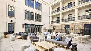 A spacious outdoor seating area with multiple sofas and tables, a brick wall, and a large window. - Charleston | Couples City Retreat | Gym + Downtown (Charleston)