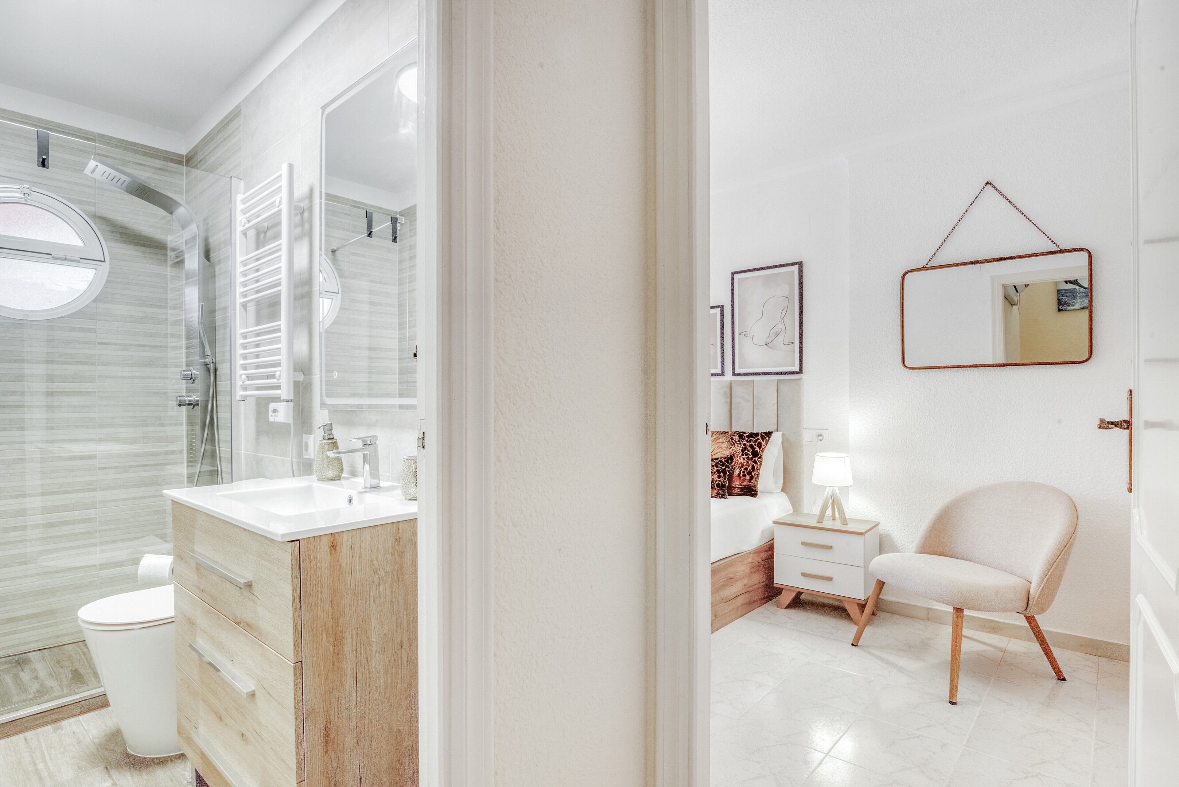 Een moderne badkamer met een douchecabine van glas, een houten wastafelmeubel, een witte wastafel en een spiegel.