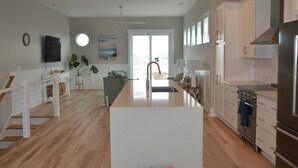 A modern kitchen with white cabinetry, a central island, and a built-in oven.