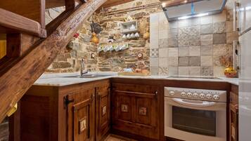 A kitchen with wooden cabinets, a stone wall, and a tiled backsplash.