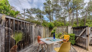 A wooden deck with a table and chairs, surrounded by a wooden fence and trees. - Charming Studio Cap Ferret Phare (Lège-Cap-Ferret)