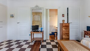 A room with a checkered floor, a bed, a wooden desk with a computer, and a mirror. - Charming Studio Cap Ferret Phare (Lège-Cap-Ferret)