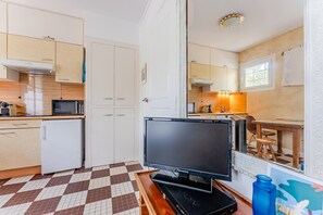 Uma cozinha compacta com micro-ondas, geladeira e uma TV de tela plana sobre um suporte de madeira.
