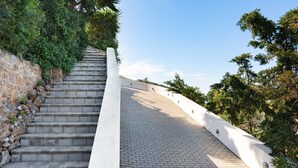 A set of stone steps leading up to a paved area with a white wall on one side and greenery on the other. - Apartment "Villa Coral - First Floor" with Private Pool & Wi-Fi (Chamolia)
