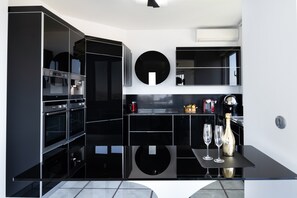 Een moderne keuken met inbouwapparatuur, een ronde spiegel en een bar voorzien van glazen en een fles.