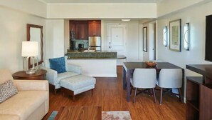 A modern living room with a sofa, a chair, a coffee table, and a dining area with a table and chairs. - Waikiki | Couples Island Stay | Pool + Spa (Honolulu)
