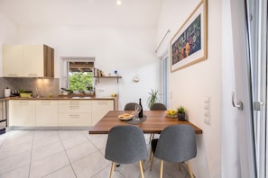 A modern kitchen with a dining table, chairs, and a window.