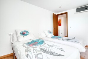 A bedroom with two beds, white bedding, and a wooden door.
