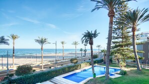 A pool with a view of the beach and ocean, surrounded by palm trees and a hedge. - Apartment 'Andres' with Sea View, Wi-Fi and Air Conditioning (El Campello)