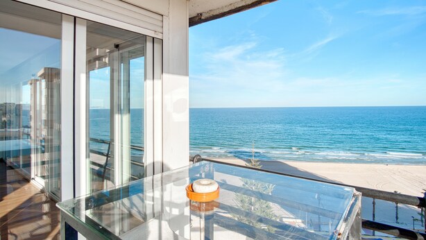 A balcony with a glass railing overlooking a beach and ocean. - Apartment 'Andres' with Sea View, Wi-Fi and Air Conditioning (El Campello)