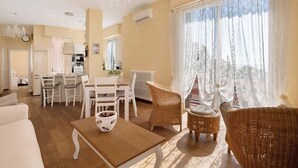 A spacious living area with a dining table, wicker chairs, a sofa, and a view through sheer curtains. - Apartment 'Amazing View' with Private Terrace, Wi-Fi and Air Conditioning (Tellaro)