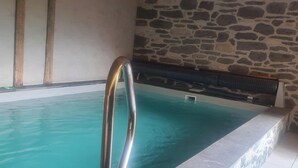 A swimming pool with a stone wall and a wooden floor. - Gîte Les Mélèzes – Mountain Views, Balcony & Wi-Fi (TERMIGNON)