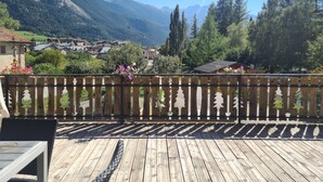 Un terrazzo in legno con vista su un villaggio e montagne.