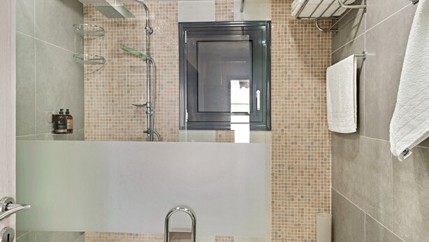 Une salle de bain avec une douche à parois de verre, un lavabo blanc et un porte-serviettes.