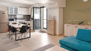 Une cuisine moderne avec un coin repas, un canapé bleu et un meuble contenant des objets décoratifs.