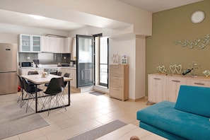 Una cocina moderna con comedor, un sofá azul y un mueble con objetos decorativos.