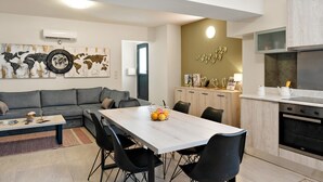 A modern living space with a dining area, kitchen, and a world map artwork on the wall. - Apartment "Theo and Ms Luxurious" with Private Terrace & Wi-Fi (Kos)