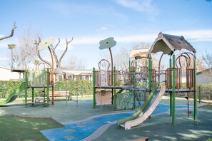 Ein Spielplatz mit Rutschen, Klettergerüsten und einem überdachten Bereich.