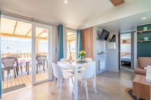 Un intérieur moderne comprenant un coin repas, un canapé, un téléviseur fixé au mur et un plafond en bois.