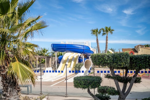Un parc aquatique doté de nombreuses toboggans et bordé de palmiers.