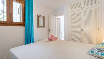 A bedroom with a bed, a window with curtains, a door, and a wardrobe.