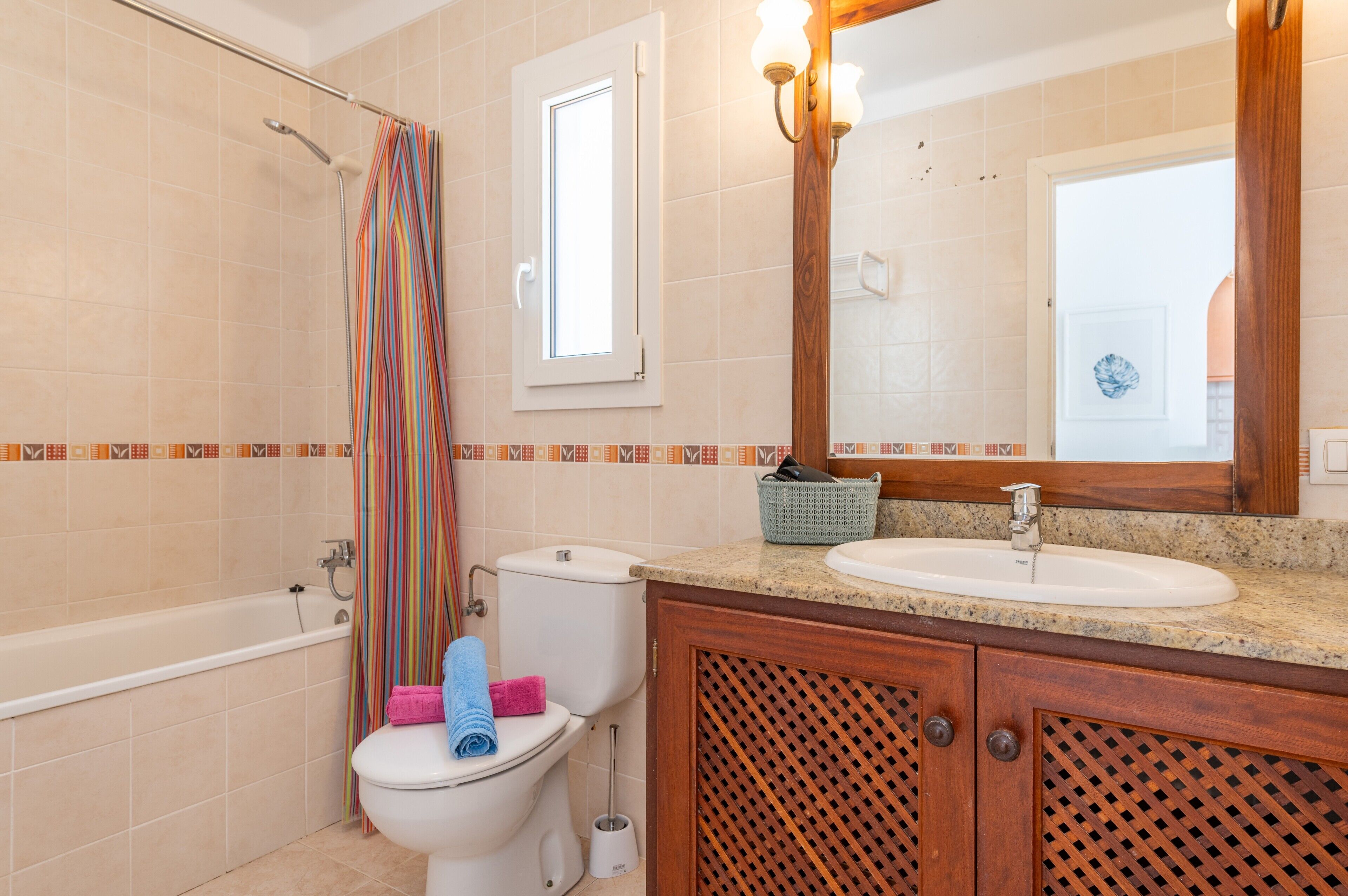 A bathroom with a bathtub, toilet, sink, and a mirror.