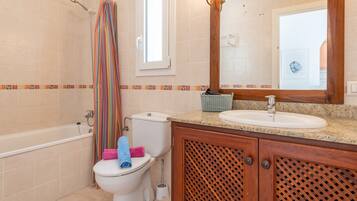 A bathroom with a bathtub, toilet, sink, and a mirror.