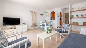 Una sala de estar con televisor, comedor, sillas y sofá.