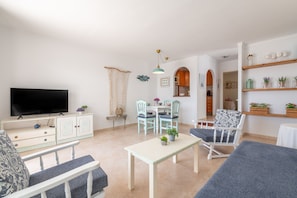 A living room with a TV, dining table, chairs, and a sofa.