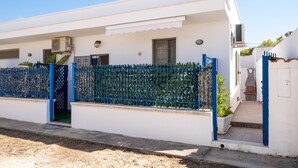 Un bâtiment blanc avec une clôture bleue, une petite entrée et une plante en pot.