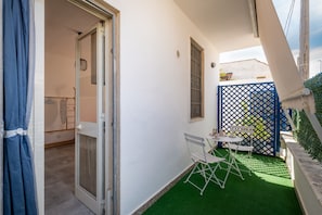 A small patio area with a table and chairs, a door leading to an interior room, and a blue lattice fence.