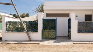 Ein modernes Gebäude mit weißer Fassade, einem blauen Tor und blauem Himmel.