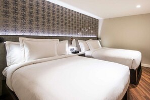 Een hotelkamer met twee bedden, een hoofdbord met een patroon en een houten vloer.