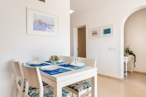 A dining area with a white table, blue placemats, and chairs with patterned cushions.