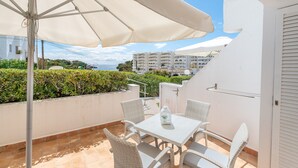 A balcony with a table and chairs, a white umbrella, and a view of buildings and greenery. - "Erizo De Mar" with Sea Views, Wi-Fi, and Air Conditioning (Tourist Tax Included) (Felanitx)